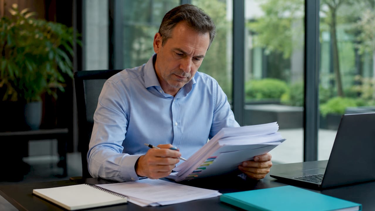 Man aan zijn bureau verdiept in het doornemen van ISO-auditrapporten