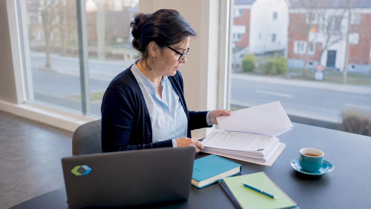 Een zorgmanager buigt zich aan zijn bureau over de HKZ-documentatie om alles goed door te nemen.