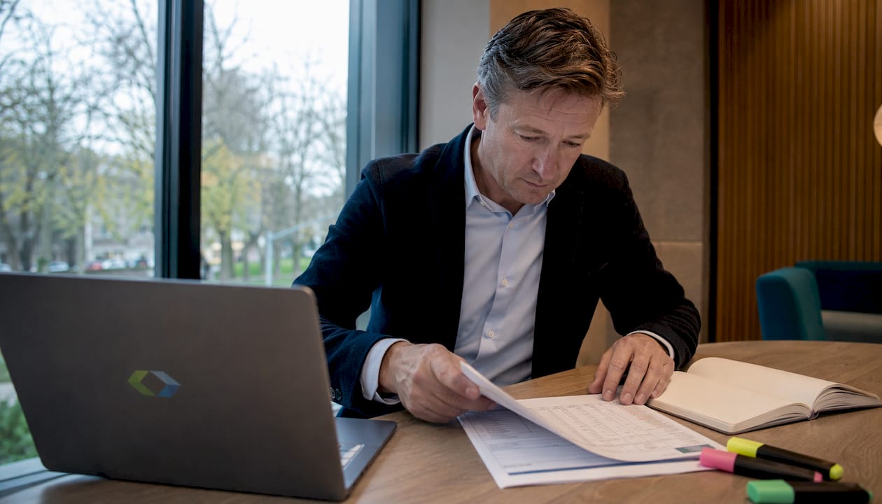 Een zakenvrouw is aan haar bureau druk bezig met het voorbereiden van documenten voor een audit.